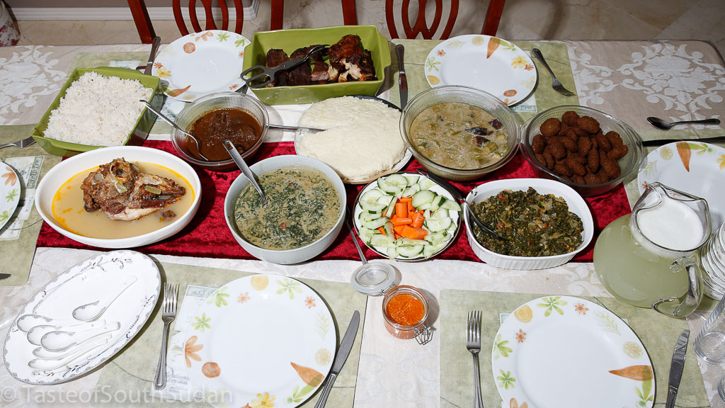 South Sudanese dinner party. Front row: fresh lemonade, Sukuma wiki, cucumber and carrots salad, spinach in peanut butter sauce, lamb head soup, Second row from Right: Rice, Doro Wat (Ethiopian spiced chicken stew), Asida, Smoked meat and okra, Tamiya, Back row: barbecue chicken and steak.
